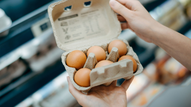 Person holding six-egg carton in grocery store