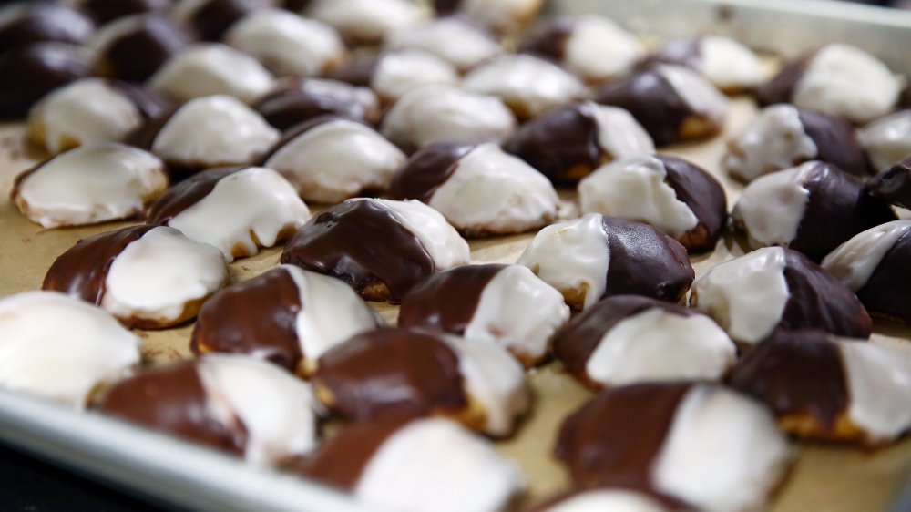 A layer of black and white cookies on brown parchment paper on cookie sheet