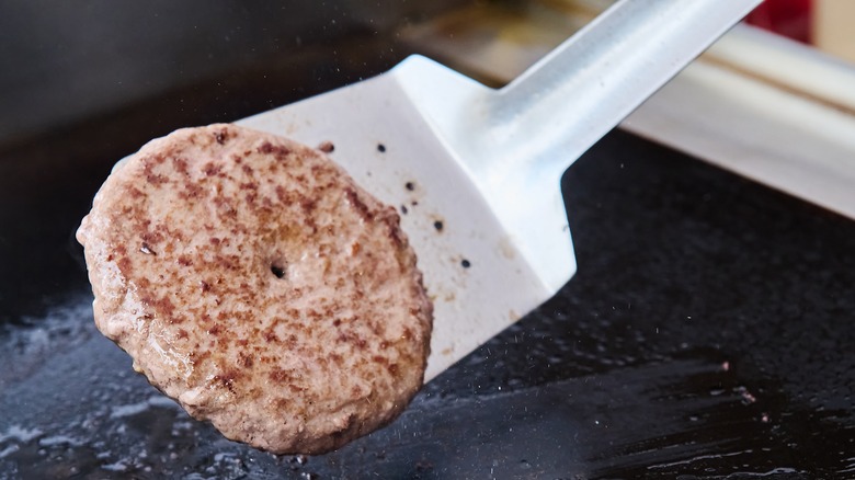 Burger patty being flipped on a griddle