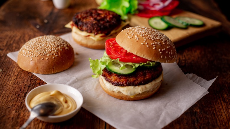 Two hamburgers and condiments on a wooden table