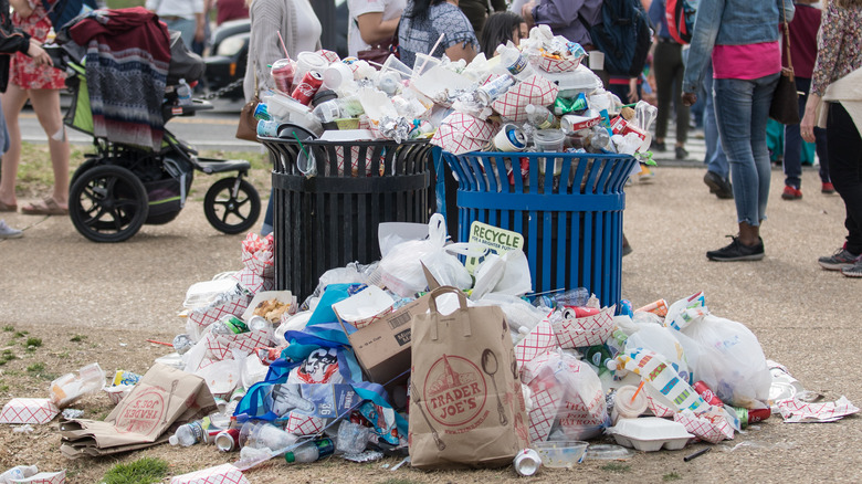 Two outdoor garbage cans overflowing with trash