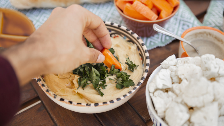 dipping carrots in hummus