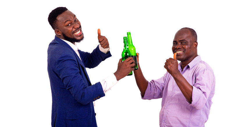 Two men holding bottle and giving thumbs up