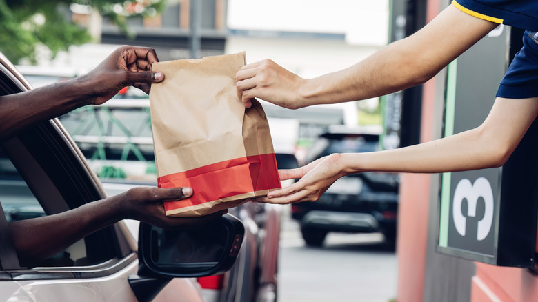 Customer in car taking fast food from worker