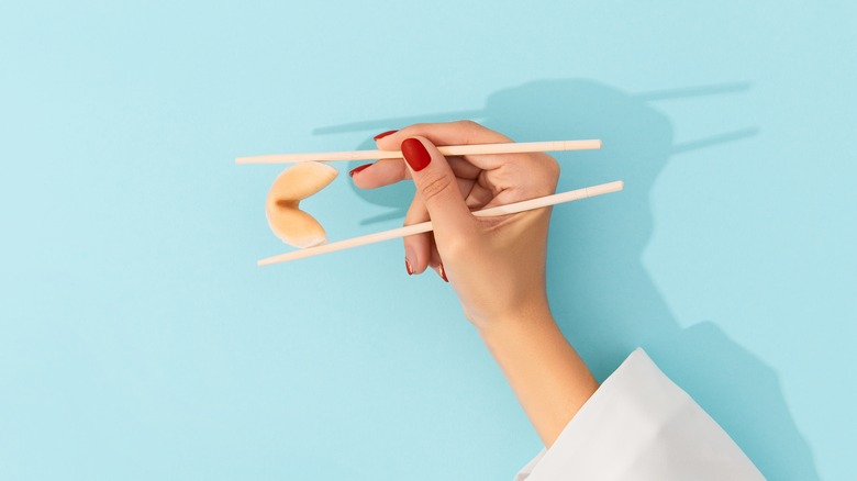 Chopsticks holding fortune cookie