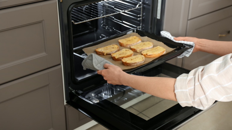 Person placing toast in oven