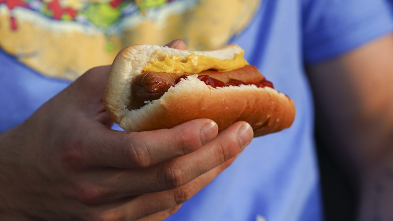 Man in T-shirt holding hot dog