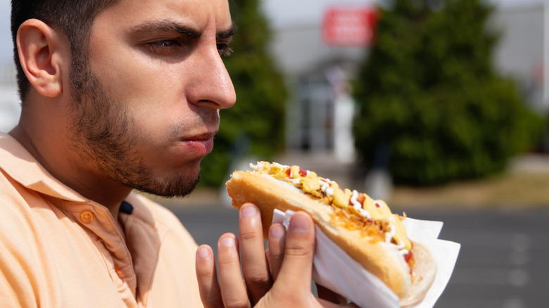 Man eating hot dog in parking lot