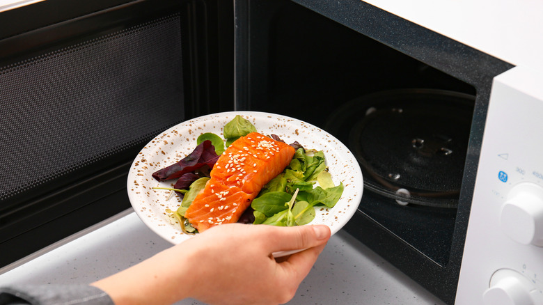 Woman cooking fish in microwave