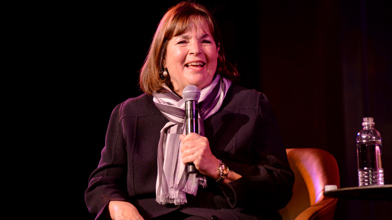 Ina Garten talking into a microphone with a spotlight on her