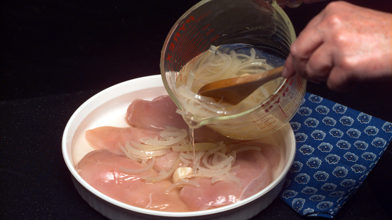 Pouring marinade over chicken breasts