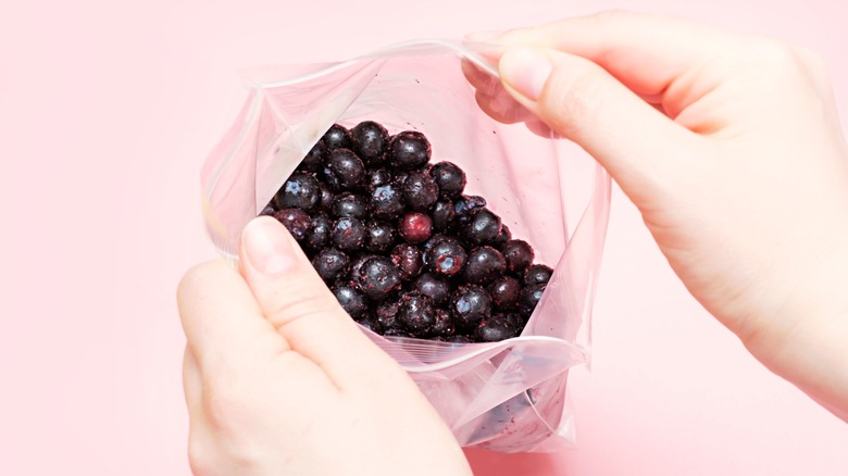Hands opening pinkish blueberry bag