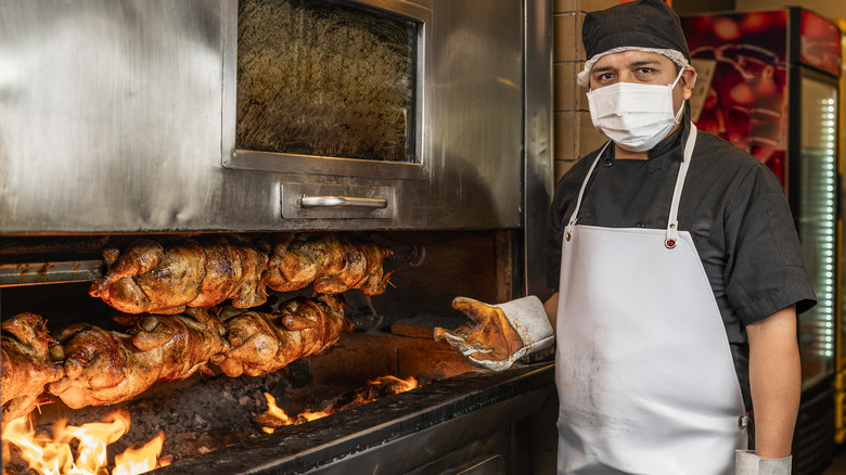 A man grills rotisserie chicken