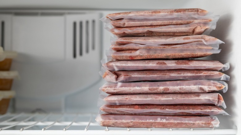 Stack of vacuum-sealed bags filled with meat inside a freezer