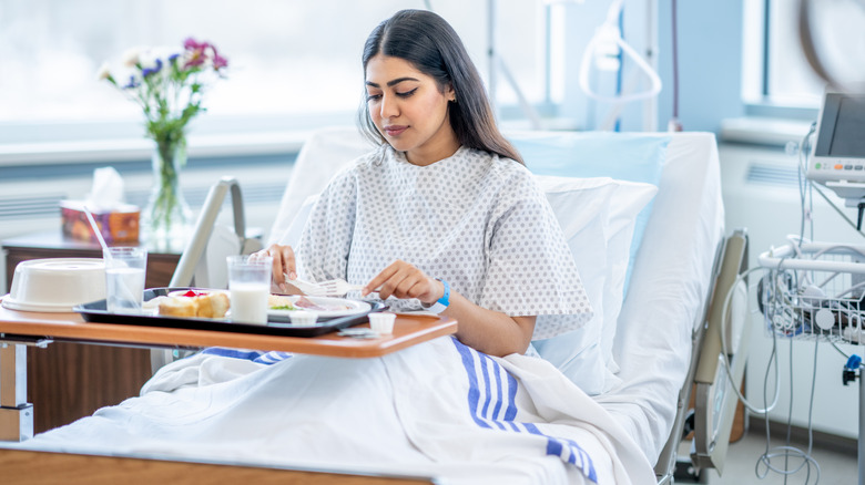 Woman in hospital eating off of tray