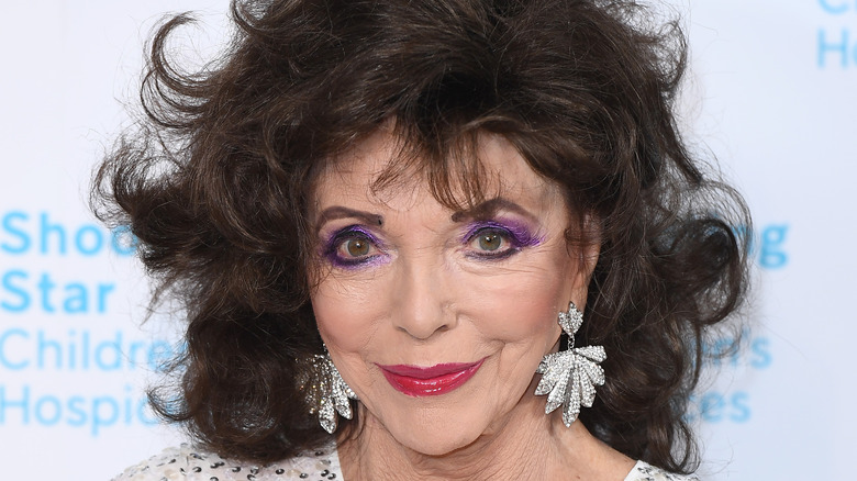 Joan Collins smiles with diamond earrings in close-up