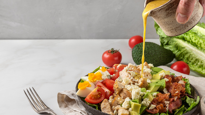 Dressing being poured over a salad