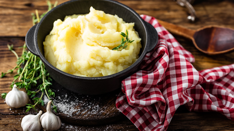 garlic and herbs by a bowl of mashed potatoes