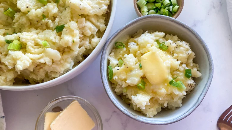 mashed potato in a dish and bowl with green onion garnish