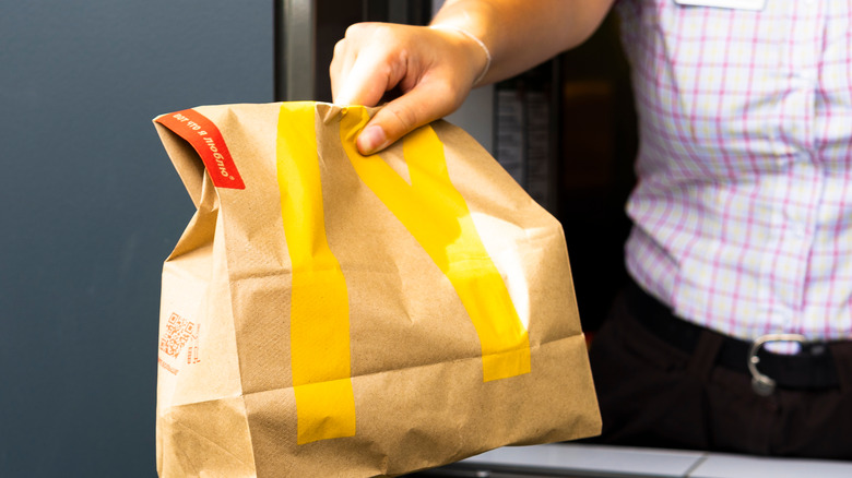 McDonald's worker handing off to-go bag at drive-thru