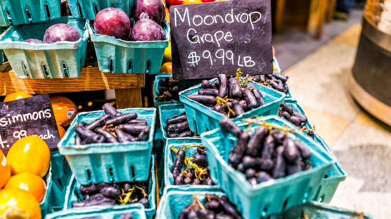 Assortment of moon drop grapes at market with sale sign