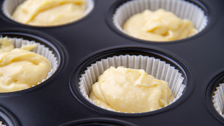 Muffin cups filled with scoops of batter