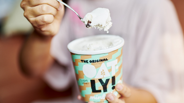 Person eating from a carton of Oatly ice cream