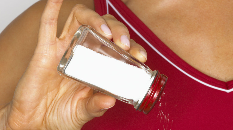 woman shaking a salt shaker