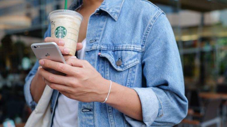 Person with Starbucks drink and iPhone