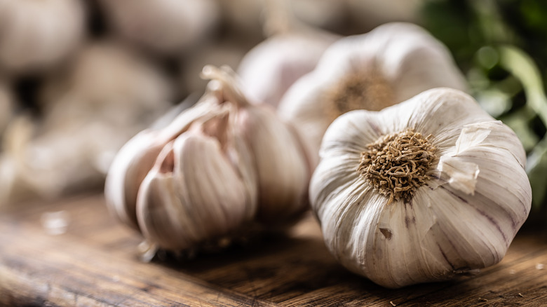 garlic heads on brown cutting board