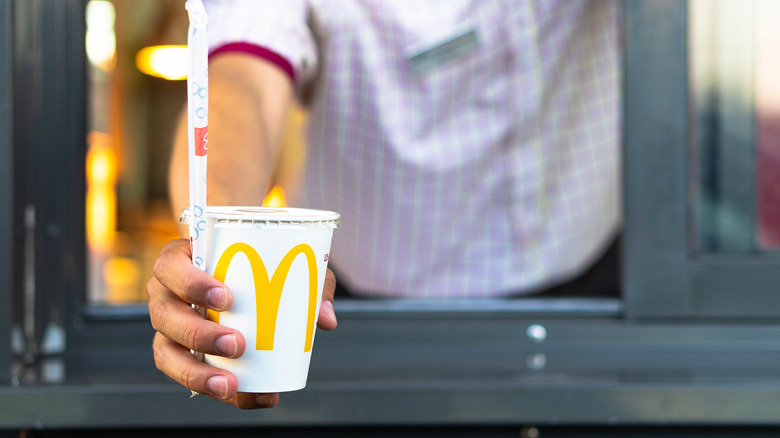 Drive-thru worker holding out a drink