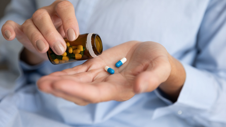 Woman taking medication from pill bottle