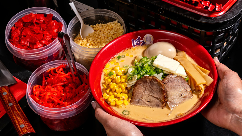 hands holding bowl of ramen