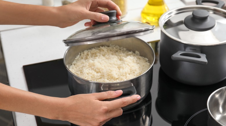 Lifting lid off pan of rice