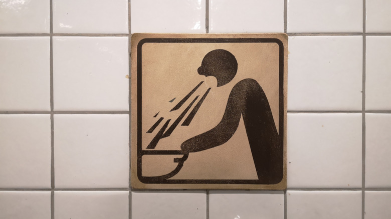 Pictorial bathroom sign of someone throwing up into a basin