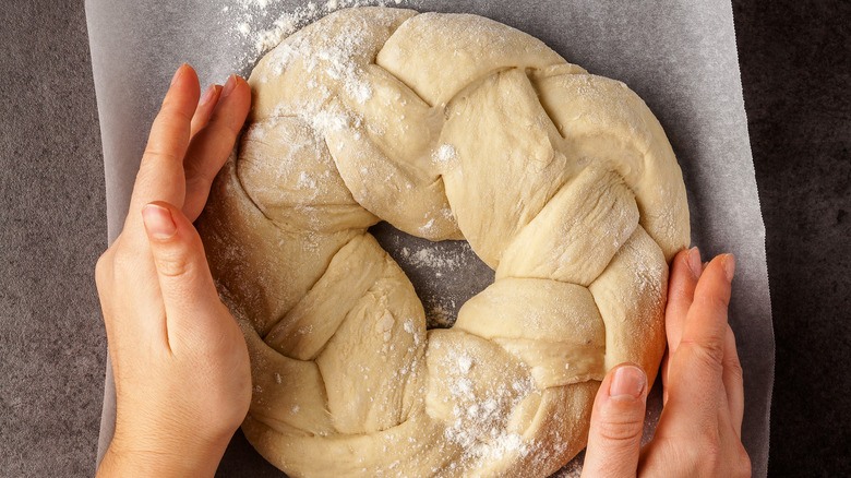 Woman forming her braided challah on parchment paper