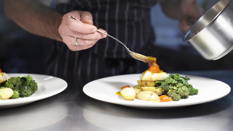 restaurant chef adding sauce to a plate