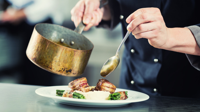 chef pouring sauce on dish