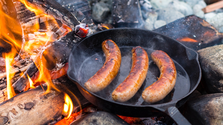 cooking sausage outdoors in cast iron pan