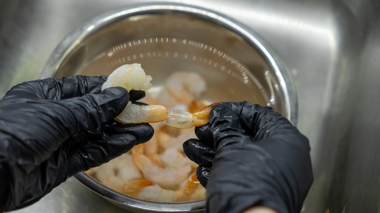 Person preparing raw shrimp