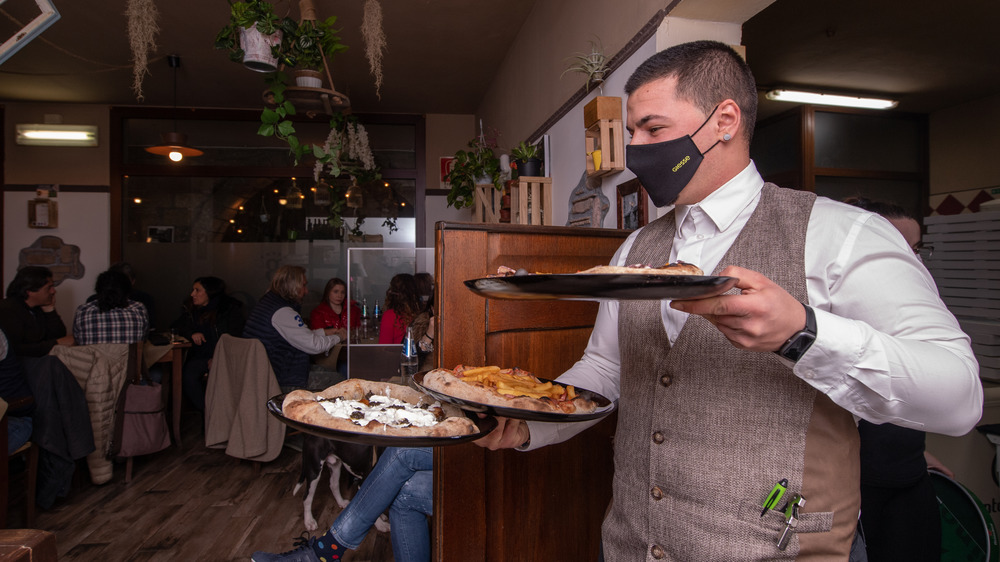 Person with mask serving pizzas