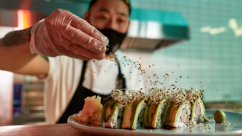 Kitchen worker prepares a sushi roll 