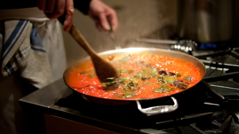 chef stirring tomato sauce