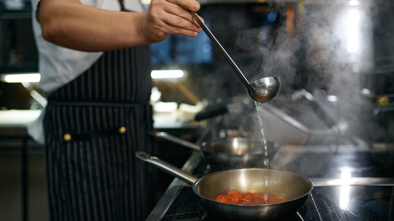 ladle of wine being added to tomato sauce