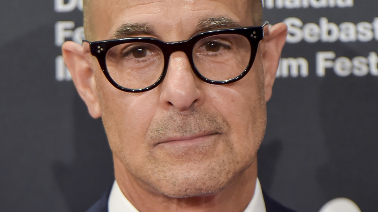 Stanley Tucci on the red carpet with glasses and serious expression