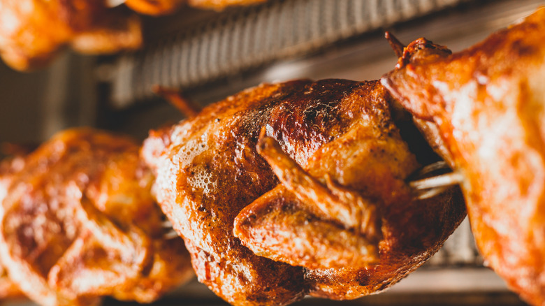 close up of chickens on a spit in a rotisserie oven