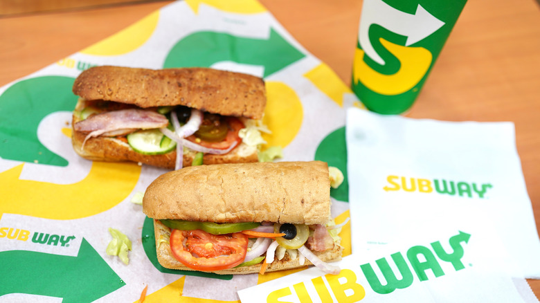 Subway sandwiches on napkins with a drink