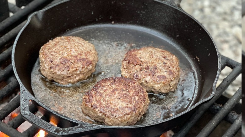 burgers cooking in cast iron pan