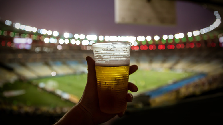 Person holding plastic beer cup in stadium