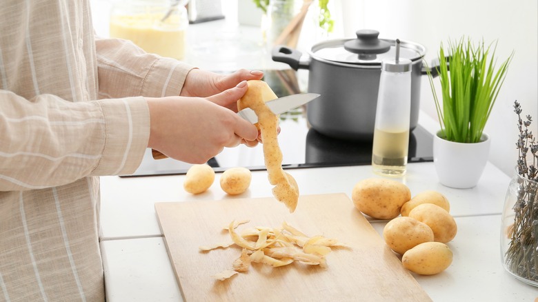 Person peeling potatoes in kitchen